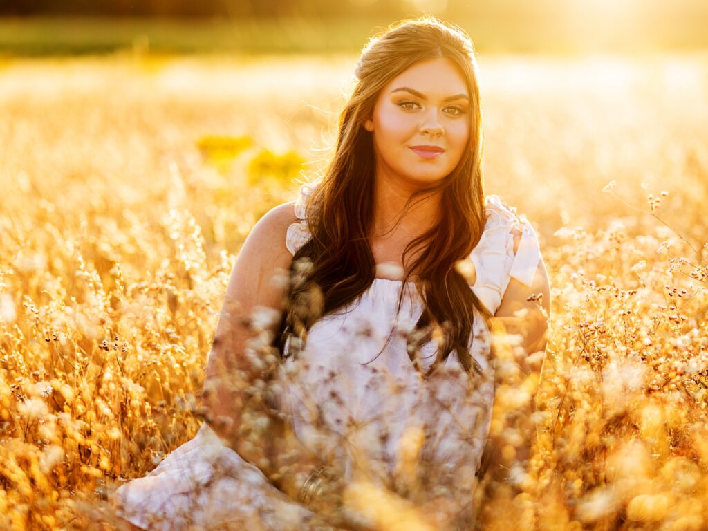 High school senior portraits of a girl in a white dress in a field during sunset in Portland Oregon