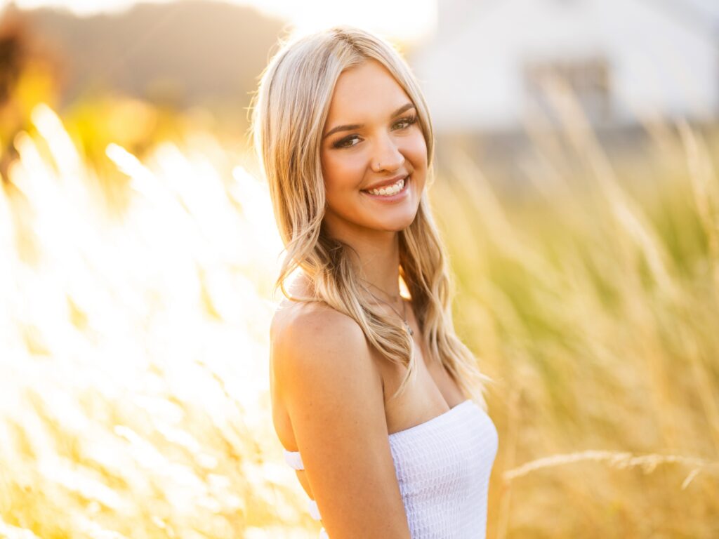 High school senior portraits of a girl in a tall grass field in Portland Oregon during sunset