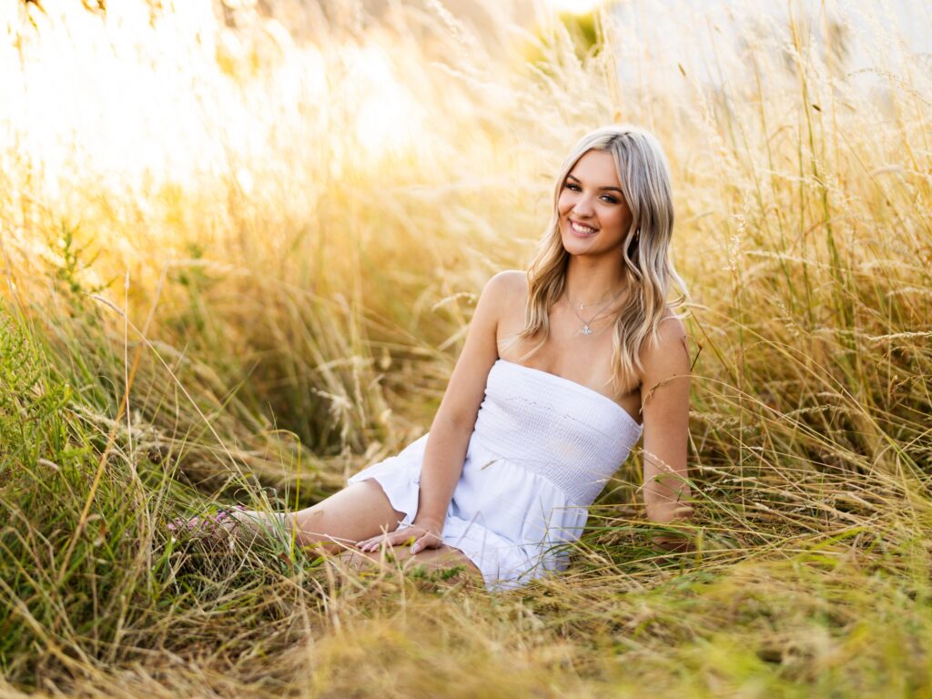 High school senior portraits of a girl in a tall grass field in Portland Oregon during sunset
