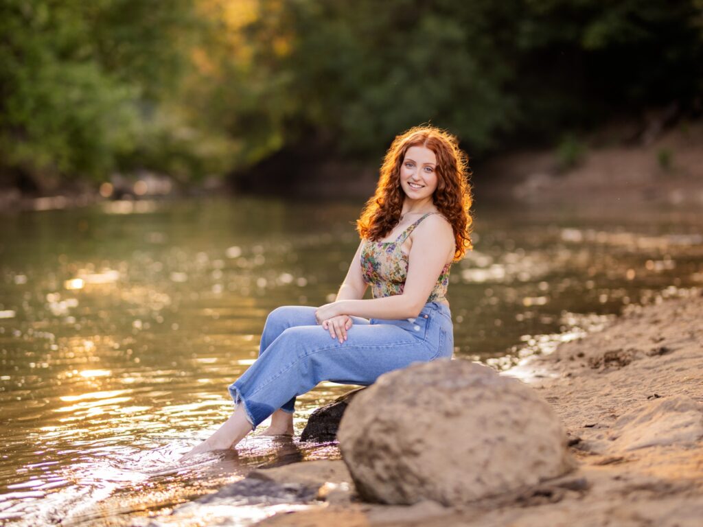 Senior portraits of a high school senior by a body of water and river during the sunset in West Linn Oregon