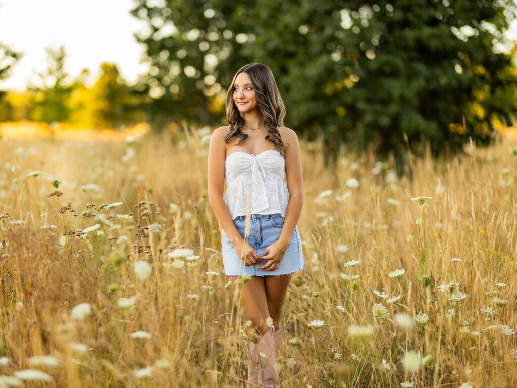 Senior photos in Vancouver Washington and Portland Oregon in the summer in a tall grassy field with a girl in a cute top and jean skirt