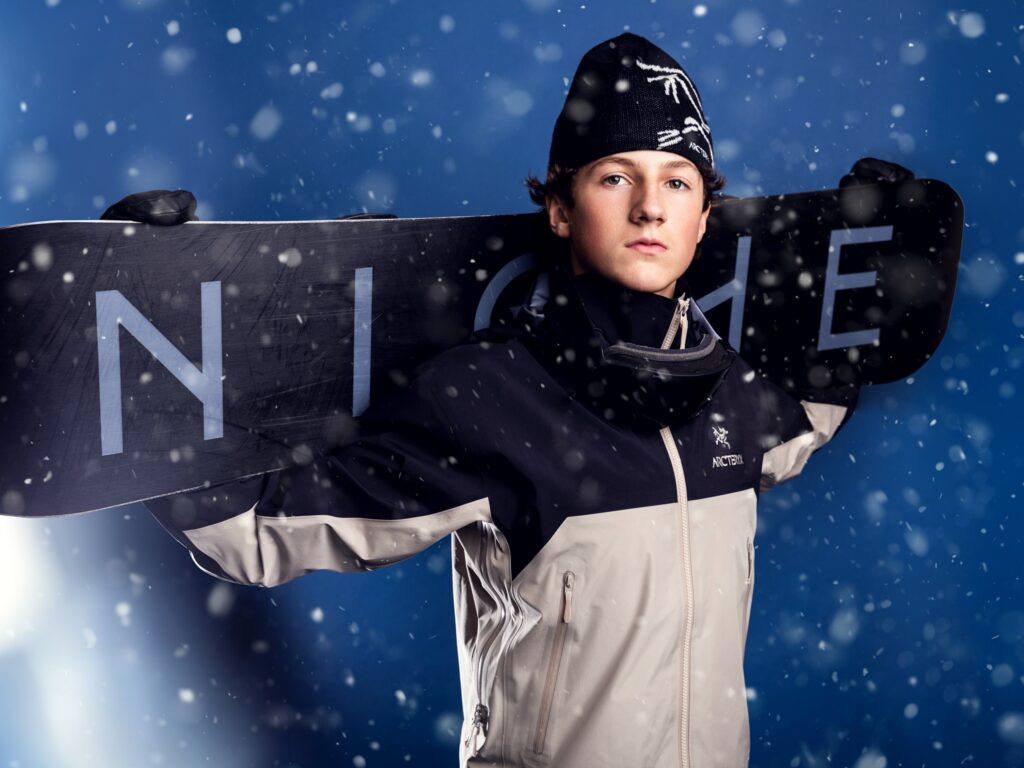 High school senior snowboard portraits in a Vancouver, WA photography studio with a blue backdrop and falling snow effect.