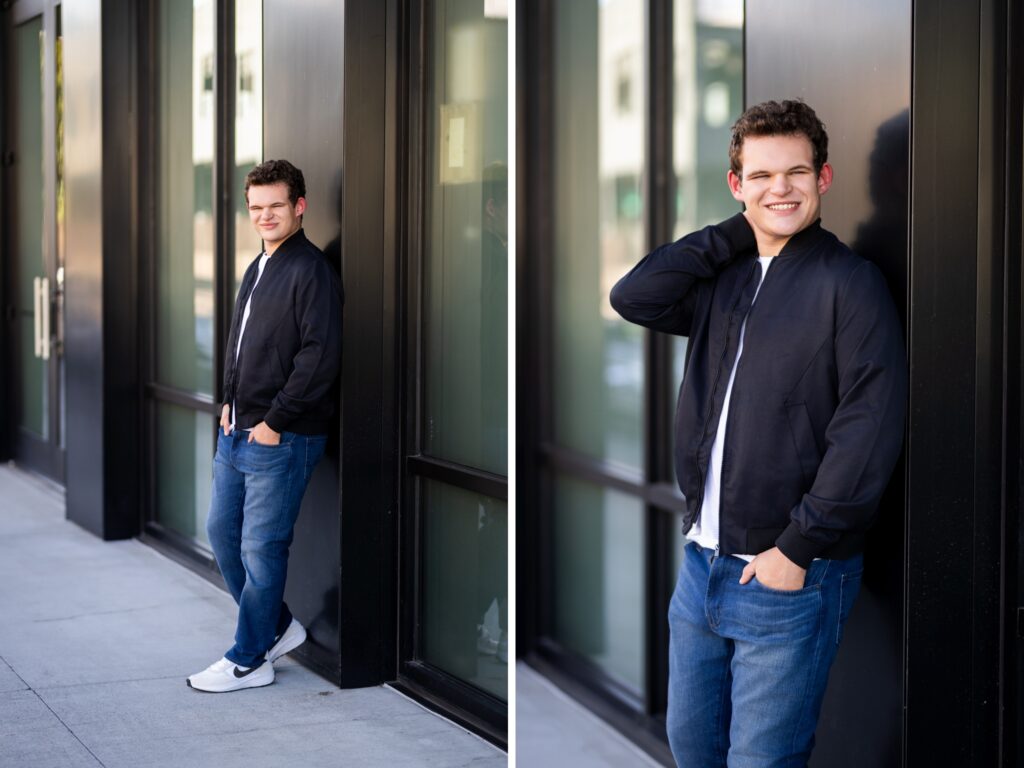 Guy senior photos in downtown Portland, OR wearing a black bomber jacket, white t-shirt, jeans, and white sneakers outside modern urban buildings.