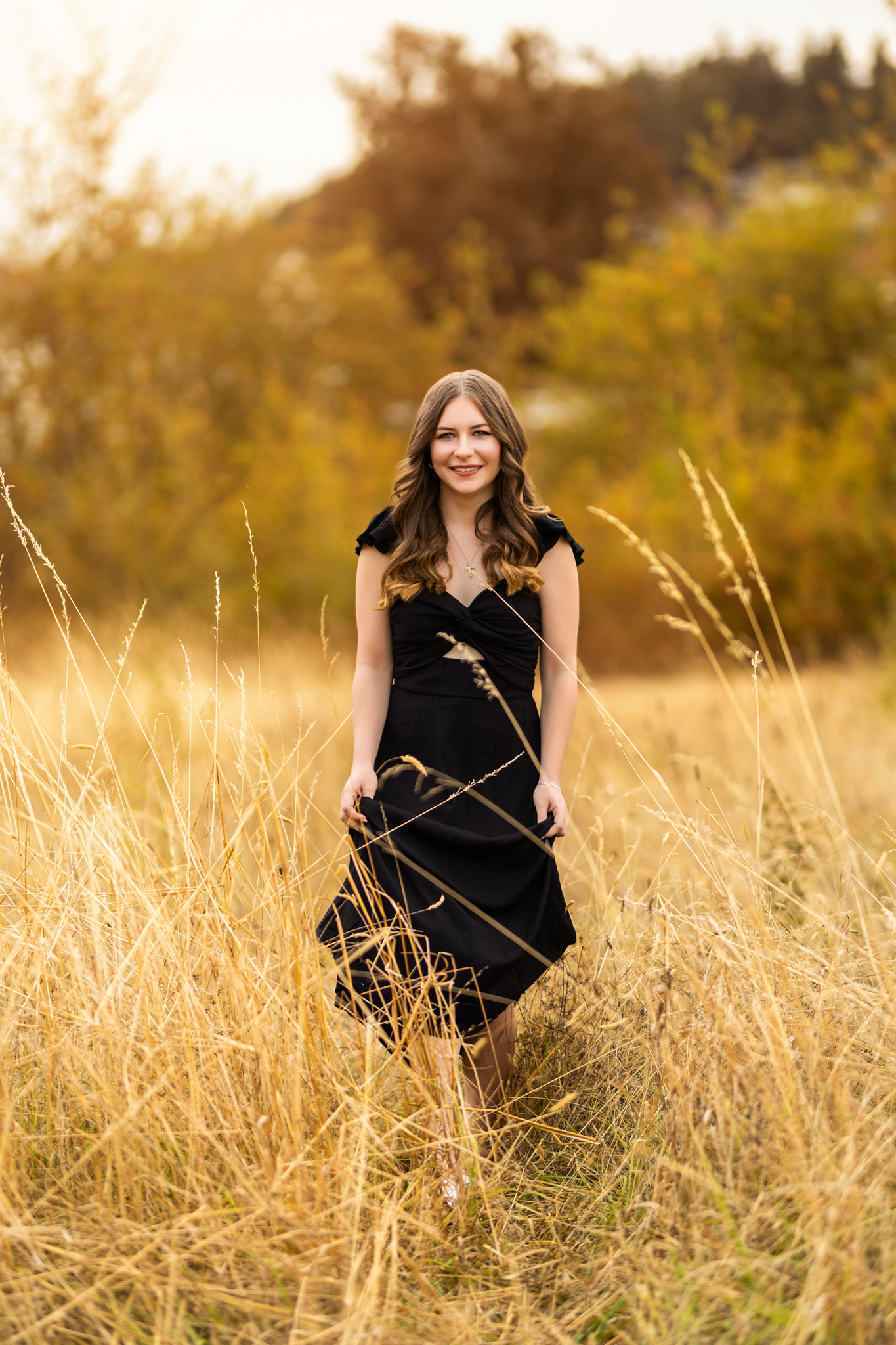 Senior photos in Lake Oswego, OR during golden hour with a black dress in a tall grass field.